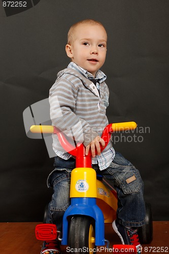 Image of Little boy riding a tricycle