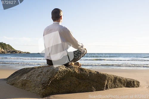 Image of Businessman meditating on a beach