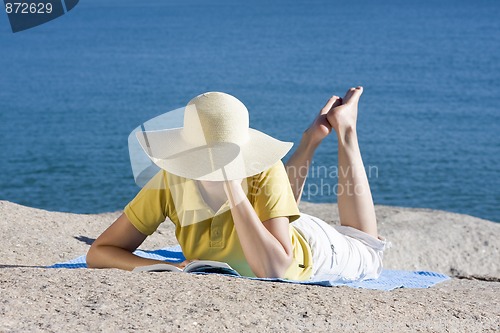 Image of Woman reading a book at the sea