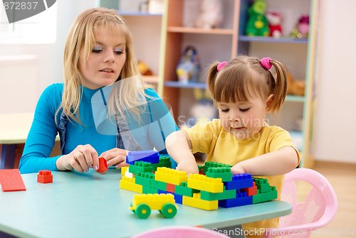 Image of Teacher and preschooler play with building bricks