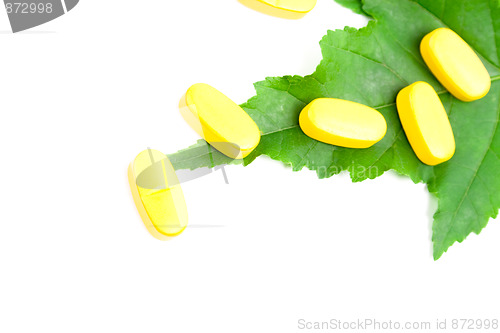 Image of yellow vitamin pills over green leaf