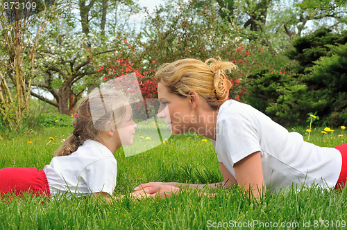 Image of Young mother and daughter laying on the grass