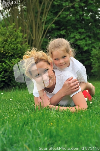 Image of Young mother and daughter laying on the grass