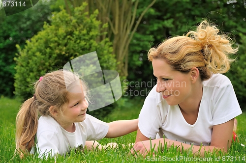 Image of Young mother and daughter laying on the grass