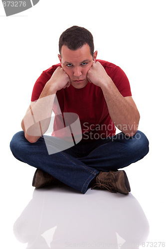 Image of upset man sitting cross-legged on the floor