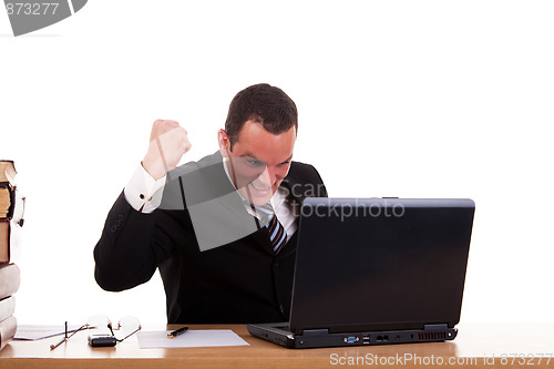 Image of businessman in front of the computer, arm raised and happy