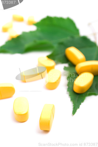 Image of vitamin pills over green leaves