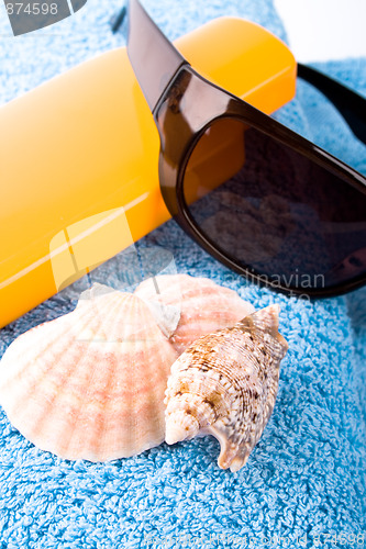 Image of towel, shells, sunglasses and lotion