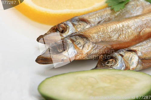 Image of Smoked fishes with lemon, cucumber and green parsley.