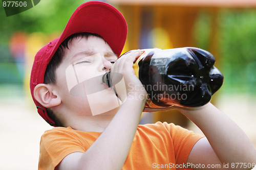 Image of Little boy drinks from big bottle