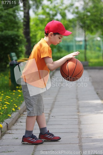 Image of Little boy dribbling basketball sideview