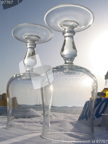 Image of View of a sailboat on the mediterranean through wine glasses on a seaside restaurant table, Mykonos, Greece