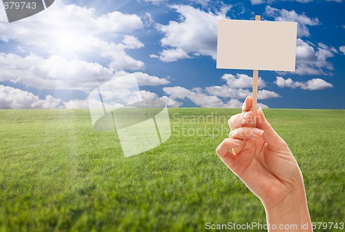 Image of Blank Sign in Hand Over Grass Field and Sky