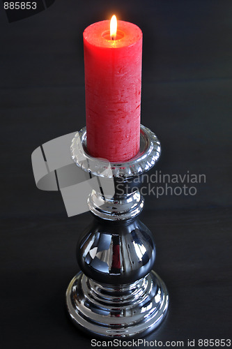 Image of Burning red candle in silver holder