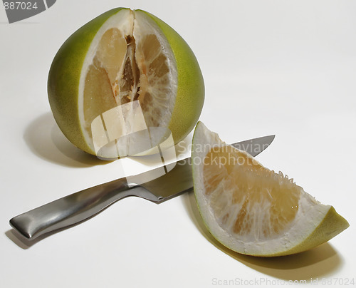 Image of Pummelo with cut out slice and knife on white