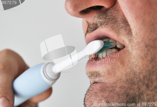 Image of Man brushing his teeth with electric toothbrush