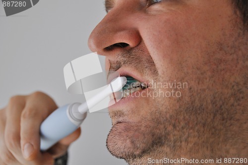 Image of Man brushing his teeth with electric toothbrush