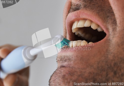 Image of Man brushing his teeth with electric toothbrush