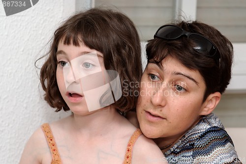 Image of Mother and cute little daughter watch TV in great concentration