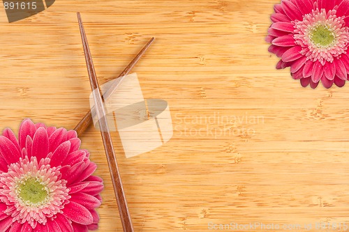 Image of Gerber Daisy and Chopsticks on a Bamboo Background