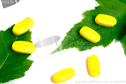 Image of yellow vitamin pills over green leaves