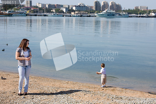 Image of Girl looks like a little boy on the shore throwing pebbles into the sea