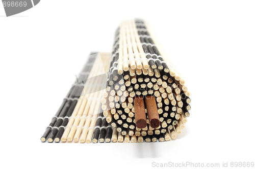 Image of Rolled bamboo mat with chopsticks isolated on white