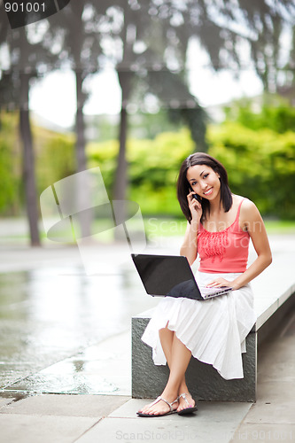Image of Woman on the phone and working on her laptop