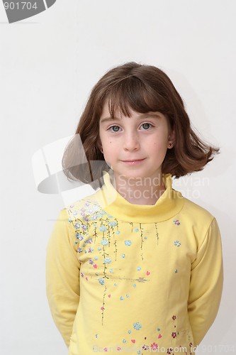 Image of Serious cute little girl stands against the wall 