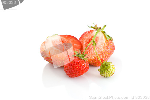 Image of One green, unripe and pair of ripe red strawberries, with one cutted on half