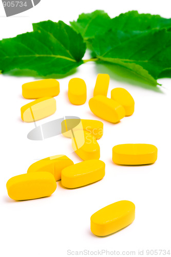 Image of yellow vitamin pills over green leaves