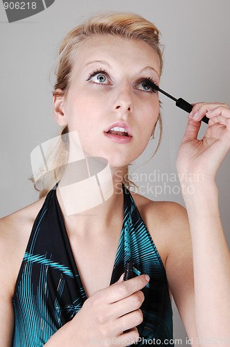 Image of Blond girl fixing her eyelashes.