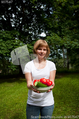 Image of Girl holding a bowl of tomato and cucumber