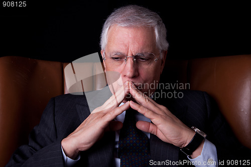 Image of old businessman  seated on a chair, thinking