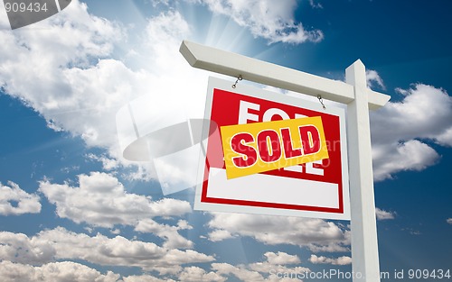 Image of Sold For Sale Real Estate Sign over Clouds and Blue Sky
