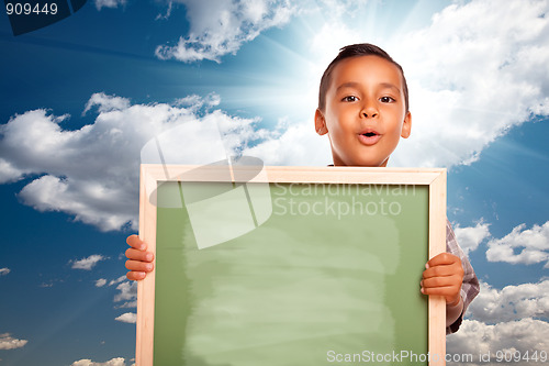 Image of Proud Hispanic Boy Holding Blank Chalkboard Over Sky