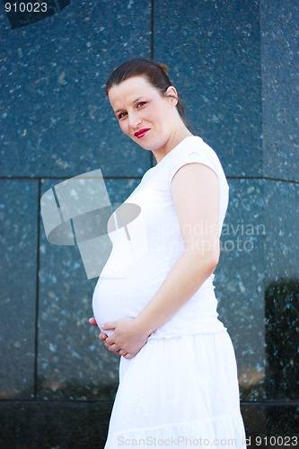 Image of Beautiful young pregnant girl holding her belly