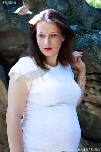 Image of Beautiful young pregnant girl with stones in the background