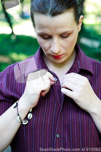 Image of Beautiful young woman buttoning