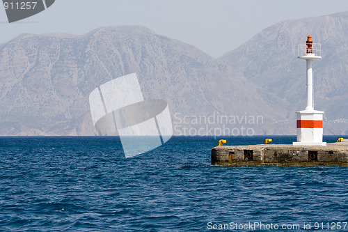 Image of Lighthouse in rocky bay against the background of mountain