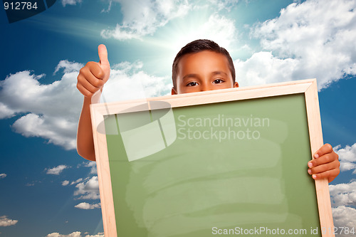 Image of Proud Hispanic Boy Holding Blank Chalkboard Over Sky