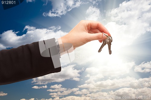 Image of Female Holding Out Pair of Keys Over Clouds and Sky