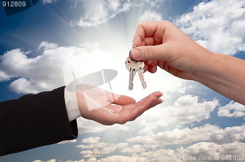 Image of Male Handing Keys to Female Over Clouds and Rays