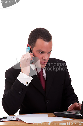 Image of businessman setting a desk talking on the phone