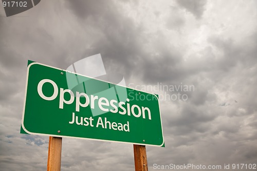 Image of Oppression Green Road Sign Over Storm Clouds