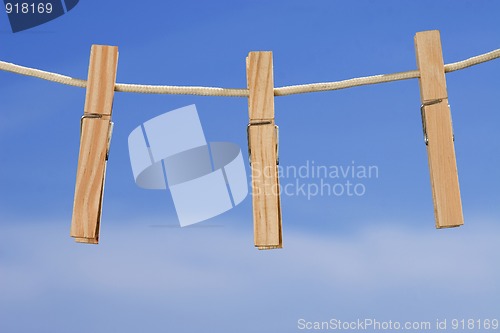 Image of clothesline and pegs on blue sky background