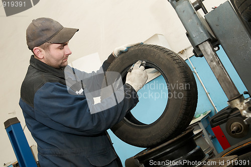 Image of repairman lubricating car tyre