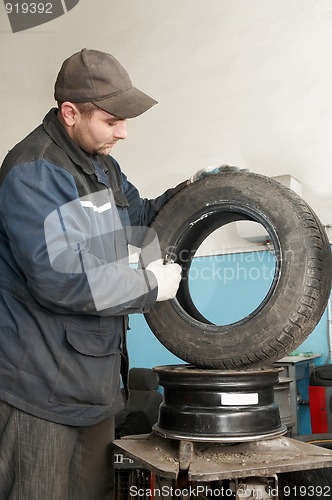 Image of repairman lubricating car tyre