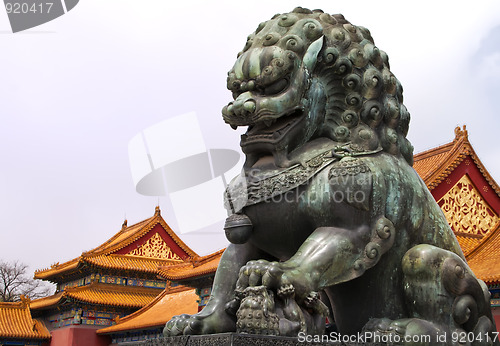 Image of Beijing Forbidden City: lion statue against the roofs.