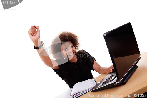 Image of young black women in front of the computer, arm raised and happy